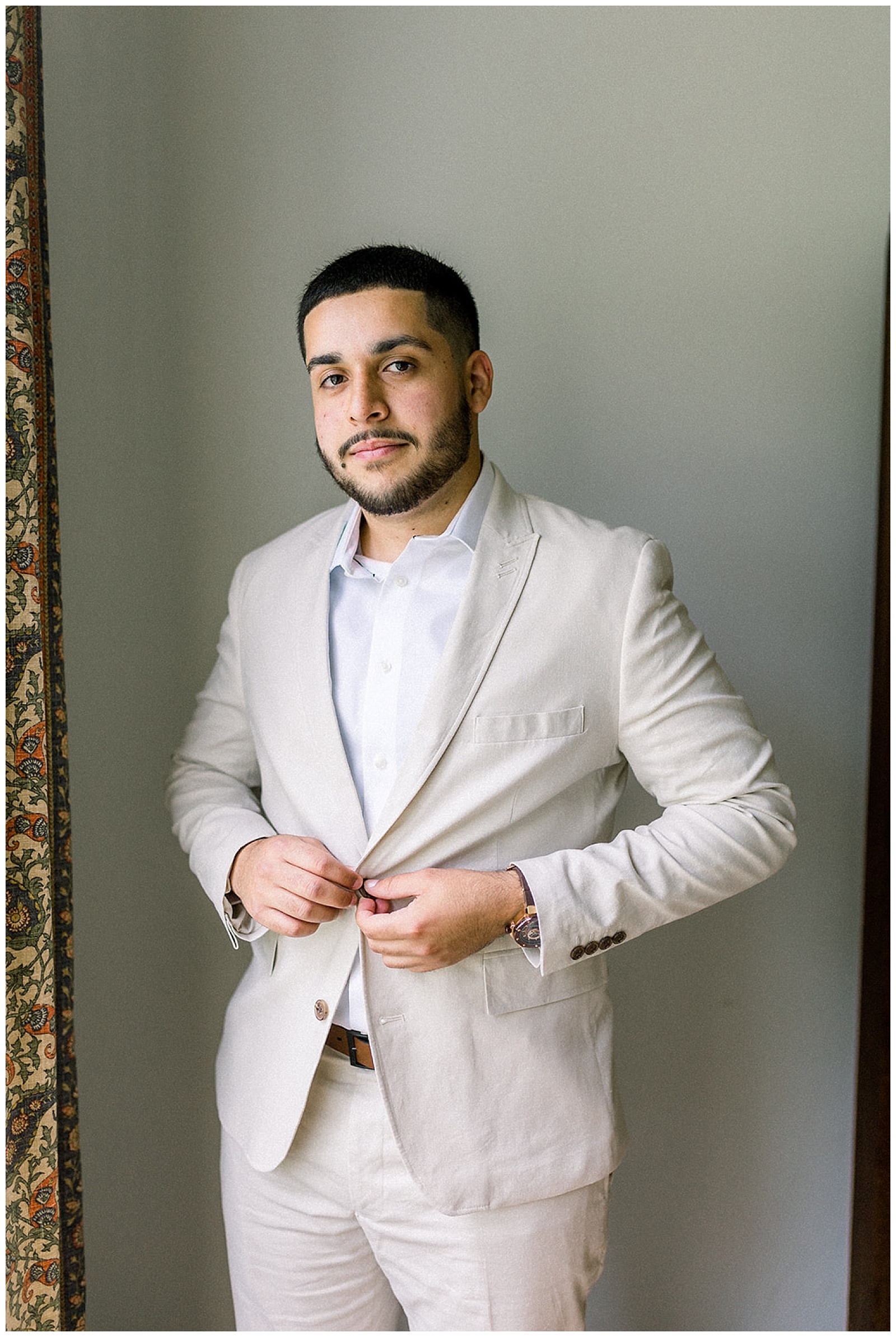 groom-to-be adjusts his watch and jacket cuffs just before his wedding ceremony, an intimate home wedding at the parents of his bride's house