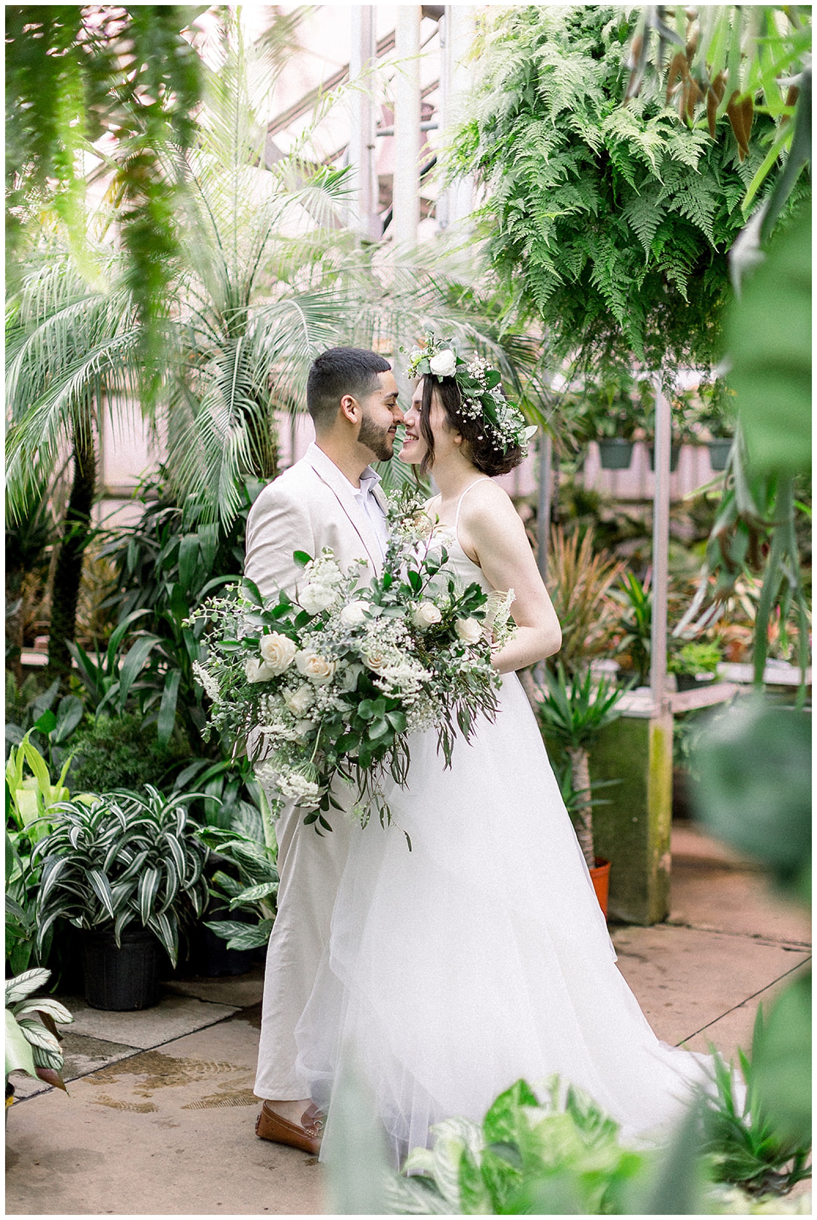 portrait of couple at otts exotic plants greenhouse in pa on their wedding day in boho wedding attire and floral crown, right before their intimate home DIY wedding ceremony