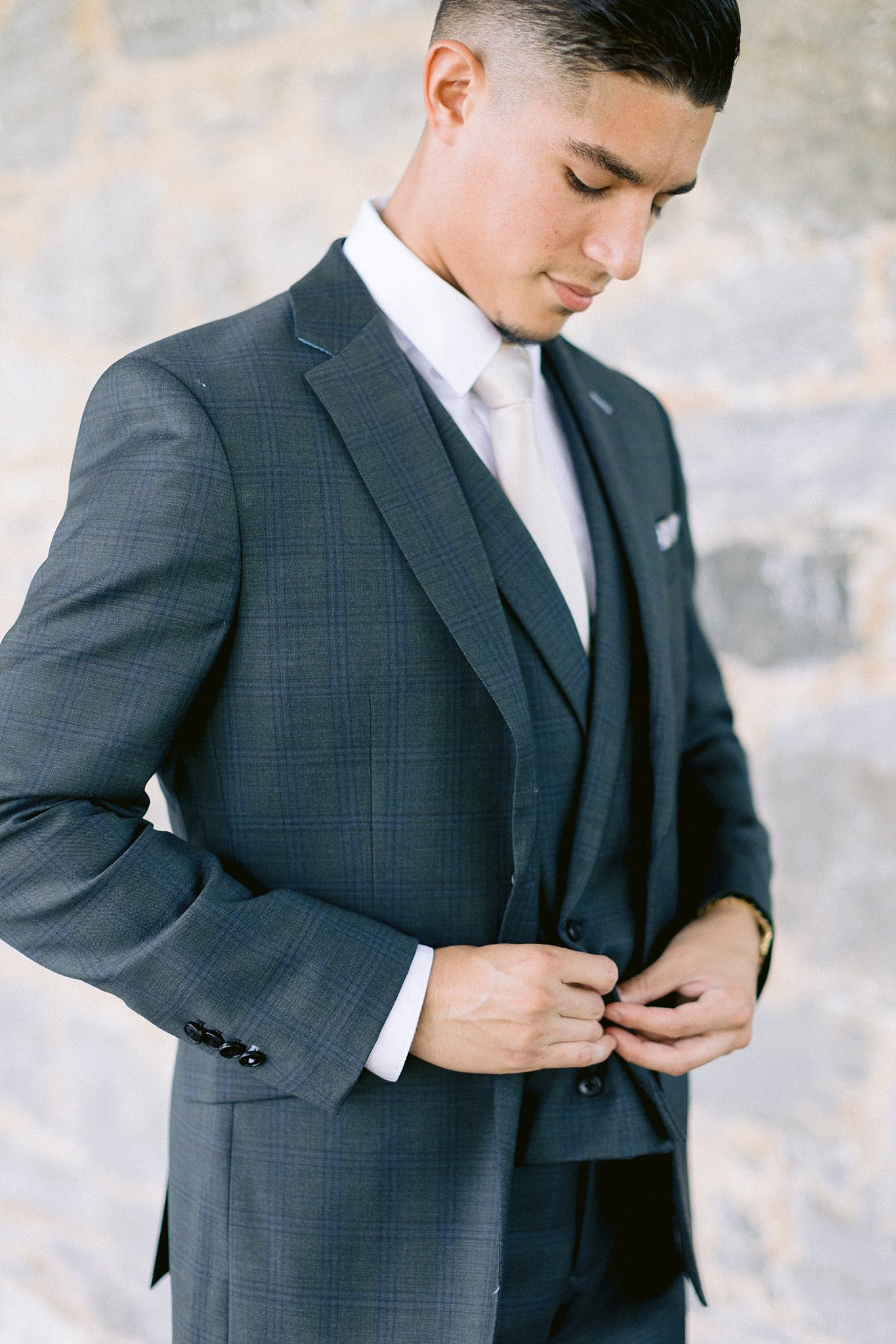 York college alumnus Anthony buttons up his vest and suit jacket to prepare for his wedding ceremony