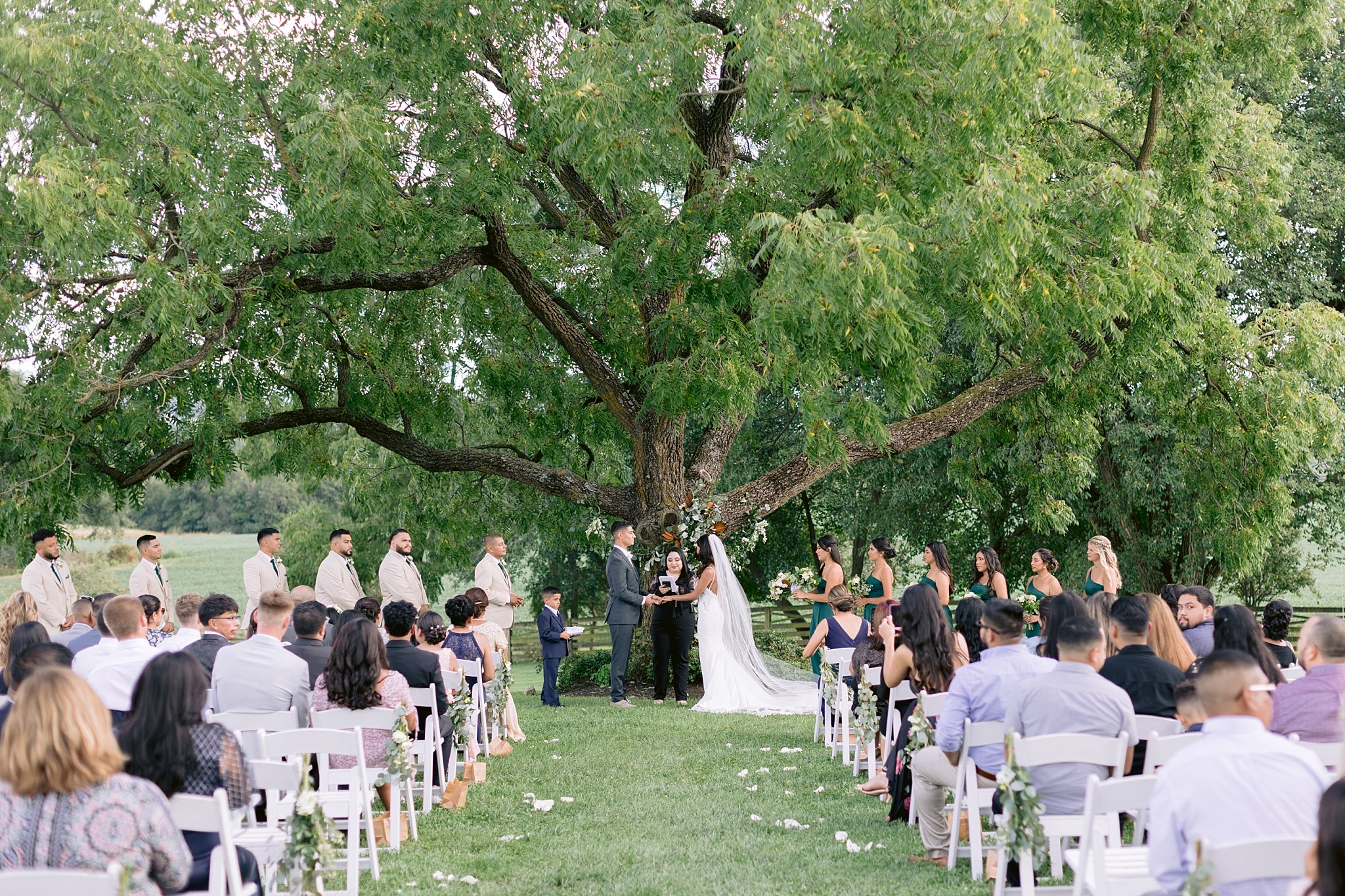 bride and groom hold hands in front of their closest friends and family during there wedding ceremony at walker's overlook